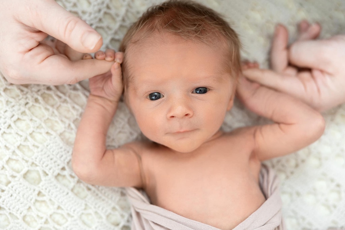 A newborn baby boy raising his hands